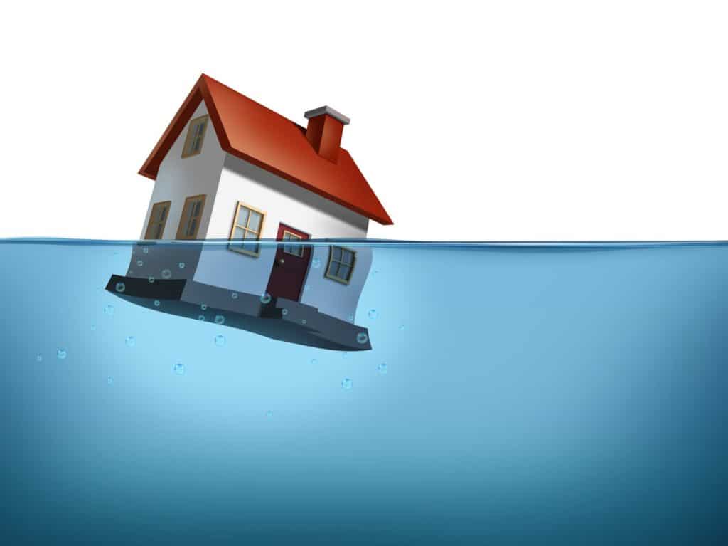Sinking home and housing crisis with a house in the water on a white background showing the real estate housing concept of the challenges of home ownership and the business of mortgage rates payments.
